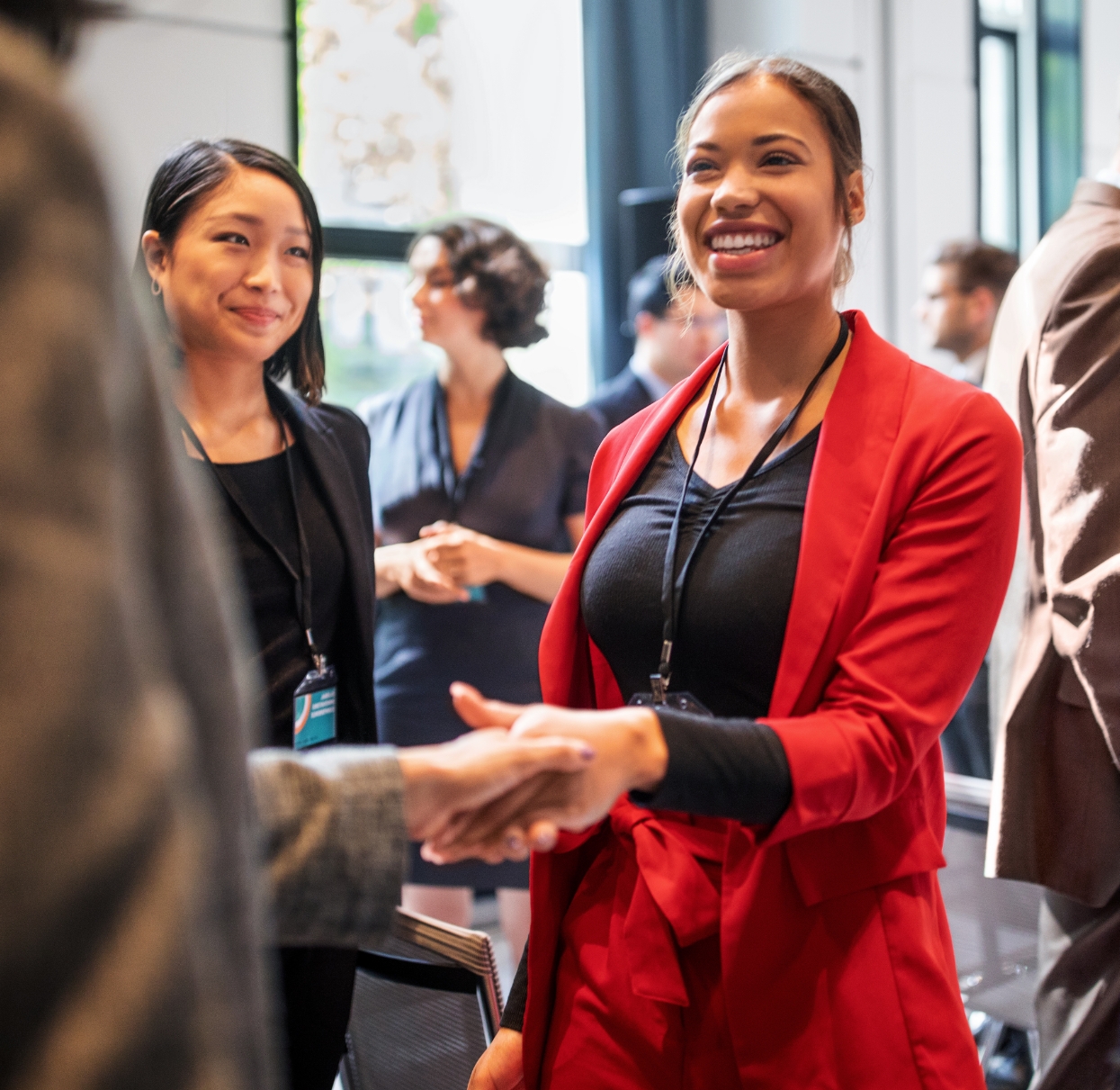 Woman professional shakes hand with another professional at a networking event